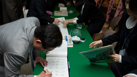 ▲ 행사장 입구에 마련된 방명록에 서명하는 내빈들.