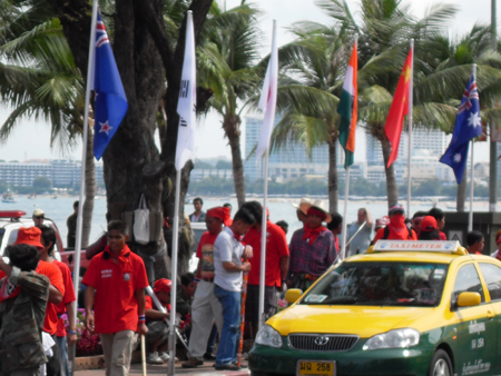 ▲ 태국 파타야에서 11일 개최될 예정이었던 '아세안（ASEAN, 동남아국가연합）+3 정상회의'가 반정부시위로 인해 무산됐다. 붉은 색 티셔츠와 머리띠를 두른 시위대가 '비치로드（Beach Road）'변에 게양된 참가국 국기를 지나 회의장인 로열 클리프 호텔로 이동하고 있다. ⓒ 뉴데일리 이길호 기자[=태국 파타야]