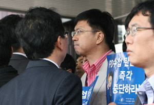 ▲ 입 꾹 다문 MBC노조원. 22일 MBC본사 현관 앞에서 서울 중앙지검 형사6부에서 나온 검찰 수사관(왼쪽 뒷모습)과 MBC노조원이 얼굴을 마주보면서 대치하고 있다. ⓒ 뉴데일리