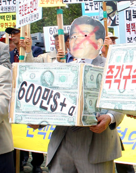 ▲ 노무현 전 대통령의 가면을 쓴 보수단체 회원이 모형 '600만달러'를 안고 있다. 노 전 대통령이 박연차 태광실업 회장으로부터 600만달러를 받았다는 의혹을 풍자했다. ⓒ 뉴데일리