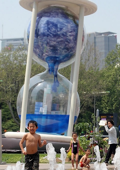 ▲ 초여름 더위가 기승을 부린 6일 오후 서울시청 분수대에서 일본 어린이들이 뛰어놀고 있다. 뒤에 보이는 조형물은 지구가 녹아 물에 잠기는 모습을 형상화한 '지구의 모래시계'. 이 조형물은 18일부터 4일간 개최되는 '서울 C40 세계도시 기후 정상회의'를 기념하기 위해 세워졌다.   ⓒ 연합뉴스