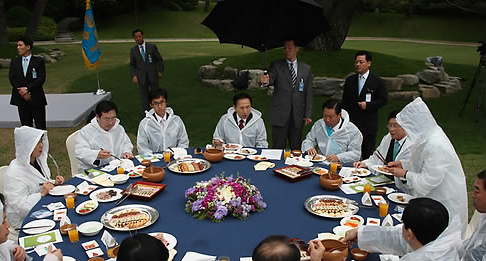 ▲ 22일 오후 청와대 녹지원에서 열린 '희망창조, 중소기업인과의 대화' 도중 비가 내리자 이명박 대통령과 참석자들이 비옷을 입은 채 행사를 진행하고 있다. ⓒ 연합뉴스