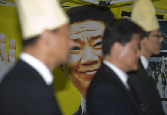 ▲ 25일 오후 덕수궁 대한문 앞에 차려진 분향소에서 상주들 사이로 웃고 있는 노무현 전 대통령의 얼굴이 보인다. <사진/황문성 기자>   ⓒ 뉴데일리