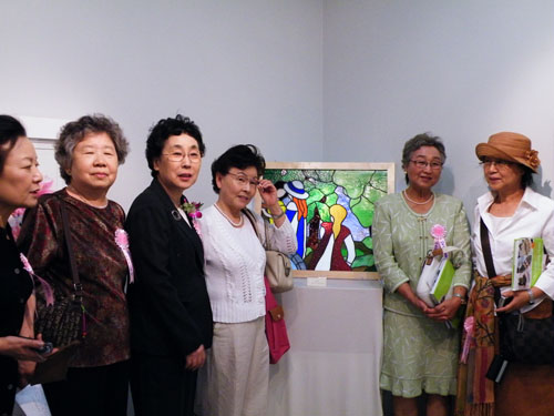 ▲ 이화여고 동창생들이 작품앞에 모여 사진을 찍고 있다. 뒤로 보이는 작품은 59회 졸업생 이광자씨의 '티파니 스타일' ⓒ 뉴데일리