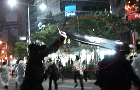 ▲ 민중의 소리가 11일 공개한 동영상 캡쳐화면. 경찰이 방팻날로 한 시위자를 가격하는 모습이 담겨있다.