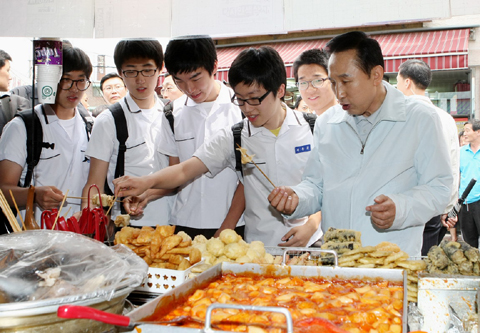 ▲ 이명박 대통령이 25일 서울 동대문구 이문동 골목상가를 방문해 떡볶이집에서 학생들과 함께 어묵을 먹고 있다. ⓒ 뉴데일리<=청와대 제공>