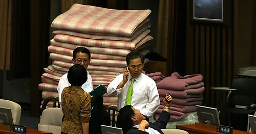 ▲ 16일 밤 국회 본회의장에 남아 있던 민주당 의원들이 퇴장에 대해 논의하고 있다. 뒤쪽에 이불이 보인다. ⓒ연합뉴스