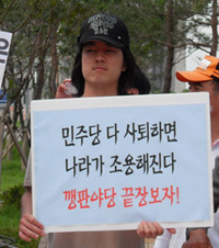 ▲ 29일 국회 앞. 한 대학생이 '민주당 다 사퇴하면 나라가 조용해진다. 깽판야당 끝장보자!'고 적힌 손피켓을 들고 있다. ⓒ 뉴데일리