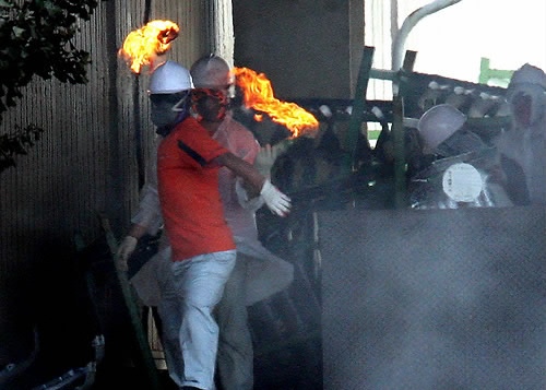 ▲ 4일 오후 경찰의 쌍용차 진압 작전이 사실상 개시된 가운데 도장공장과 차체공장을 연결하는 통로의 완성차를 치우려는 사측과 경찰을 향해 노조원이 화염병을 던지고 있다.&nbsp; ⓒ&nbsp;연합뉴스