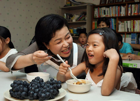▲ 이명박 대통령 부인 김윤옥 여사는 4일 경기 고양시 일산소재 '기쁨터' 지역아동센터를 방문, 관계자들을 격려하고 봉사활동에 참여했다. 한&nbsp;어린이에게 직접 요리한 궁중떡볶이를 먹이고 있는 김 여사. ⓒ 뉴데일리 <=청와대 제공>