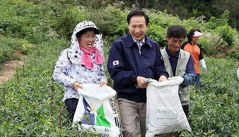 ▲ 이명박 대통령이 11일 강원도 홍천군 내촌면 고추밭에서 수확한 고추를 농민들과 함께 옮기며 웃고 있다. ⓒ 연합뉴스