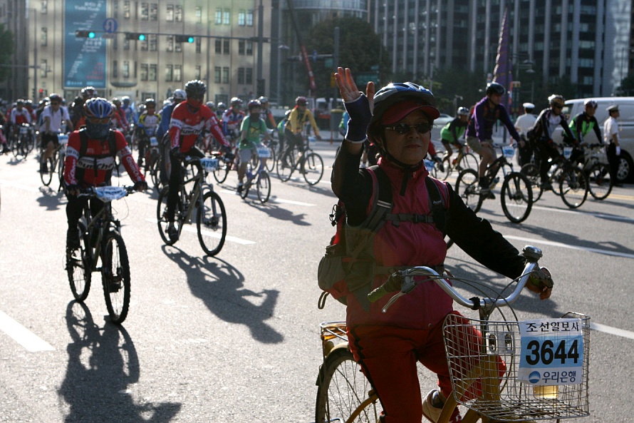 ▲ 손을 흔들며 자전거를 타고 있는 한 여성시민. ⓒ 뉴데일리