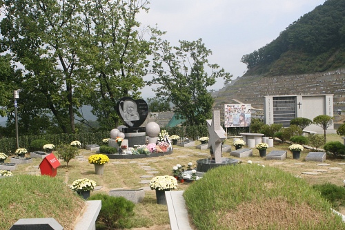 ▲ 고 최진실의 유골함이 분실되는 초유의 사고를 당한 이후 갑산공원은 최진실의 납골묘를 원기둥 형태로 교체하고 별모양의 조형물과 함께 묘역 주위에 고인이 생전 출연했던 영화 포스터를 새긴 평판을 전시하는 등 고인을 추억할 수 있는 다양한 소품들로 장식해 눈길을 끌었다. 공원 관계자는 