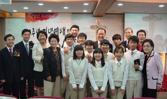 ▲ 두리하나 국제학교 개교식에 참석한 인사들이 학생들과 자리를 함께 했다. 오른쪽 끝이 김주 교장, 그 뒤에 천기원 목사, 십자가 앞에 황우여 의원, 왼쪽 끝이 김윤태 목사, 그 옆에 김세연 의원, 이혜훈 의원. ⓒ 뉴데일리