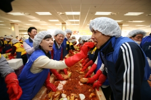 ▲ 21일 사랑의 김장나누기 행사에 참여한 삼성전자의 한 직원이 프로축구 수원삼성의 중국출신 리웨이펑 선수에게 직접 담근 김장김치를 맛보이는 장면. &nbsp;ⓒ 뉴데일리
