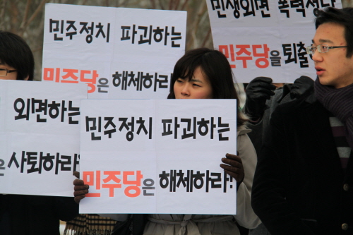 ▲ 추운 날씨에도 불구하고 '전국환경단체연합' 대학생 회원들 50여명이 29일 오후 12시 국회 앞 공원에서 '민주정치 파괴하는 민주당은 해체하라' 등의 문구가 담긴 피켓을 들고 시위를 벌이고 있다. ⓒ 뉴데일리