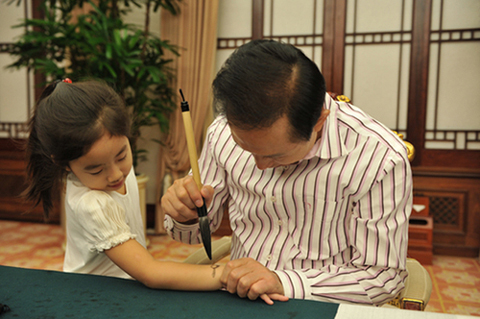 ▲ 관저에서 서예연습을 하던 이명박 대통령이 손녀의 팔목에 진지한 표정으로 시계를 그려주는 모습이 재미있다. ⓒ 뉴데일리 <=청와대 사진기자단 보도사진전>