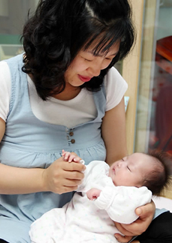 ▲ 넷째 아이를 낳고도 출산장려금 지원기준 때문에 한푼도 받지 못한 유숙자(44)씨가곤히 잠든 넷째 아이 예담이의 손을 꼭 잡고 있다&nbsp;ⓒ&nbsp;연합뉴스