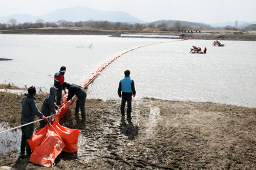 ▲ 16일 경북 구미시 해평면 해평취수장에서 열린 &lsquo;4대강사업 오염사고 대비훈련&rsquo;에 참가한 한국수자원공사와 구미소방서 등의 관계자들이 오일펜스를 치고 있다. ⓒ 윤한나 그린리포터