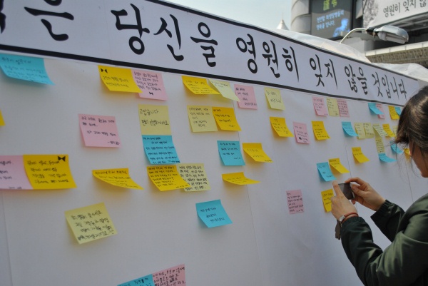 ▲ 순국장병들에게 메시지를 남기는 대형 게시판에 시민들이 깨알같은 글씨가 적힌 메모지를 붙이고 촬영을 하고 있다.&nbsp; ⓒ 뉴데일리