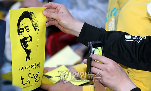 ▲ 9일 저녁 광주 동구 금남로 옛 전남도청 앞 광장에서 열린 노무현 대통령 추모 콘서트에서 한 시민이 노 전 대통령의 얼굴을 휴대전화에 담고 있다.