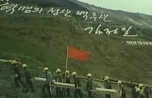 ▲ 백두산 암벽에 '혁명의 성산 백두산, 김정일 1992년 2월 16일 새김'이라고 새겨진 김정일 국방위원장의 글발 아래를 천지 돌계단 공사용 돌을 짊어진 노동자들이 지나가고 있다. ⓒ&nbsp;연합뉴스