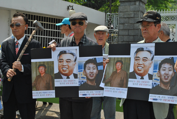 ▲ 보수시민단체는 20일 천안함 침몰원인이 '북의 소행'으로 밝혀지자 국방부 앞에서 김정일-김일성-김정은(왼쪽부터)사진을 들고 나와 규탄 집회를 벌이고 있다.ⓒ 뉴데일리