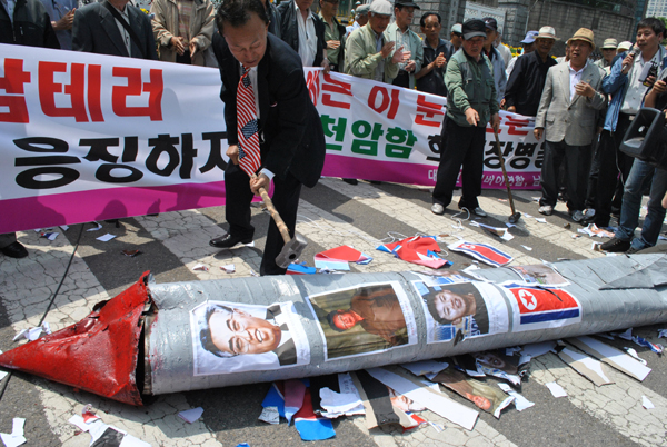 ▲ 보수시민단체 회원들은 어뢰모형에 김일성-김정일-김정은(왼쪽부터) 사진을 붙여, 망치로 부수는 퍼포먼스를&nbsp;진행하고 있다. ⓒ 뉴데일리