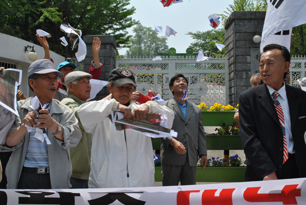 ▲ 보수시민단체 회원들은 북한 김일성, 김정일, 김정은의 사진을 찢어 공중에 날리고 있다. ⓒ 뉴데일리