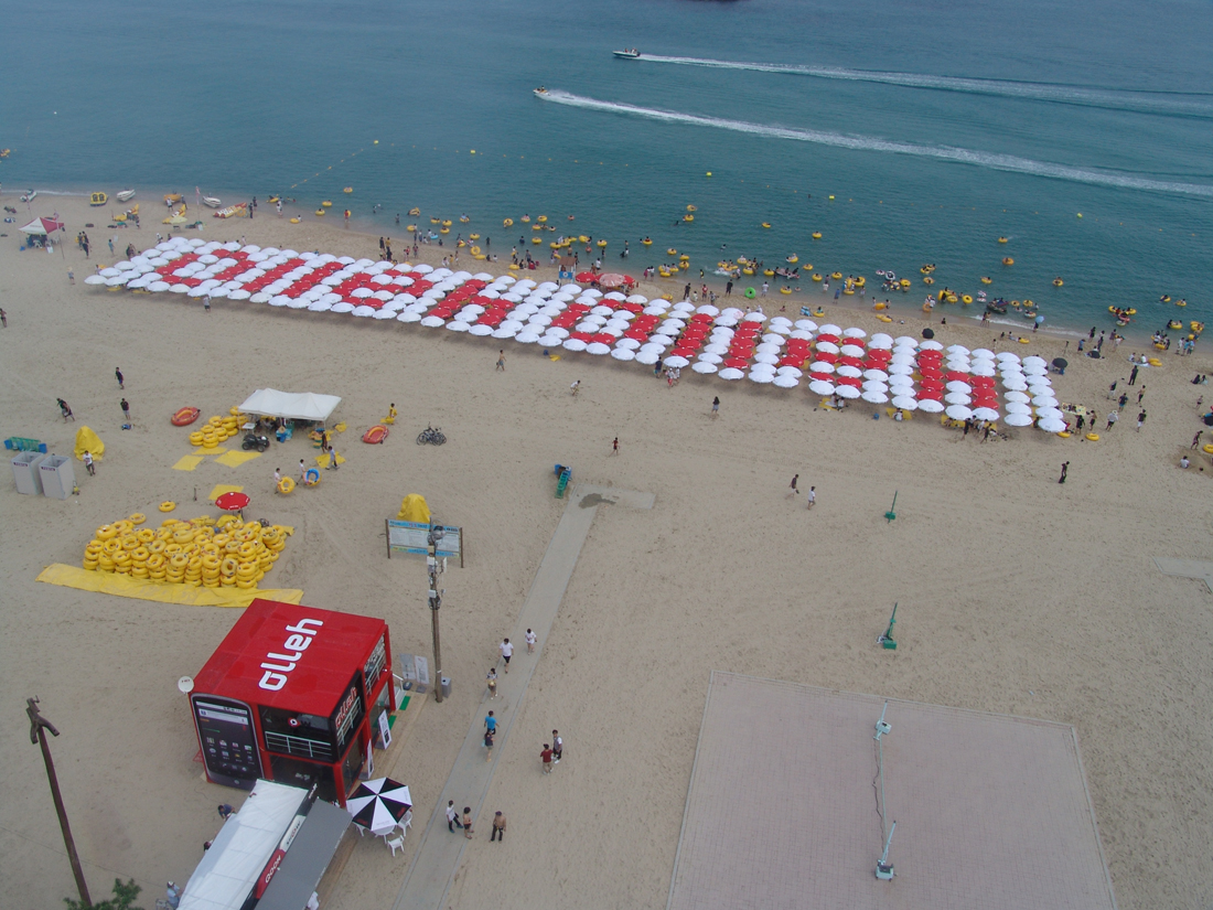 ▲ KT는 지난 주말부터 다음달 15일까지 강릉 경포 해변에서 여름 휴가철 해수욕장 방문 고객을 위해 해수욕장 내 와이파이 서비스 및 구글 넥서스원 체험 행사 등을 진행한다. 이를 기념해 경포 해변 백사장의 파라솔을 모자이크 형식으로 배치해서, 하늘에서 봤을 때 &lsquo;olleh&rsquo;라는 글자가 해변을 따라 새겨지도록 연출했다. ⓒ 뉴데일리