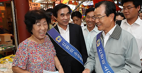 ▲ 신한미소금융재단은 지난 17일 '서울망우지부'를 개점했다. 라응찬 신한금융지주 회장(앞줄 오른쪽)이 시장상인에게 안내장을 배포하며 미소금융을 알리는 모습 ⓒ 연합뉴스