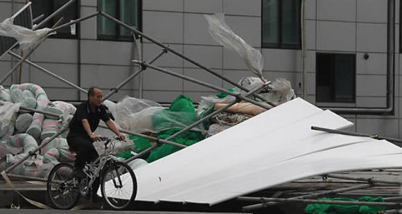 ▲ 태풍 곤파스가 한반도를 강타한 2일 오전 서울 용산 한강로의 한 공사장 외벽이 강풍에 무너진 가운데 한 시민이 자전거를 타고 그 옆을 지나가고 있다.ⓒ연합뉴스