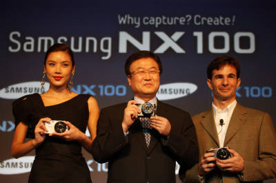 ▲ (왼쪽부터) 홍콩 톱모델 게일리라이(Gaile Lai), 삼성전자 박상진 사장, 내셔널 지오그래픽 사진작가 타이론 터너(Tyrone Turner)가 삼성전자의 미러리스 카메라 신제품 '삼성 NX100'을 소개하고 있다.ⓒ뉴데일리