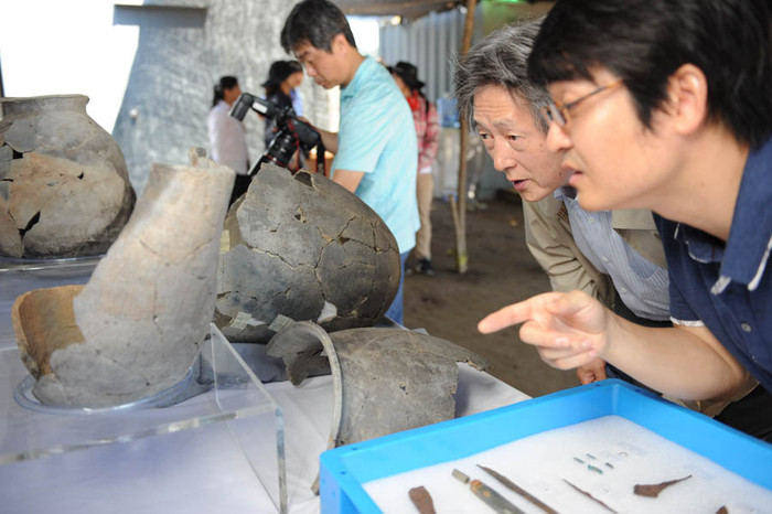 ▲ 발굴단 관계자들이 백제유물을 살펴보고 있다.