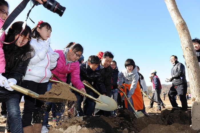 ▲ 어린이들이 팽나무에 흙을 퍼 넣고 있다. 가운데있는 어른은 이충재 서울지방국토관리청장.