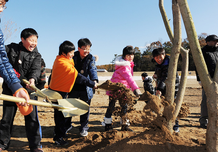 ▲ 나무에 흙을 북돋우며 즐거워하고 있는 어린이들.