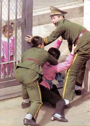▲ 2002년 5월11일 선양의 일본 영사관으로 달려들어가는 탈북자 여인을 중국 공안이 막고 있다. 철장안의 딸이 지켜보고 있다.(자료사진)