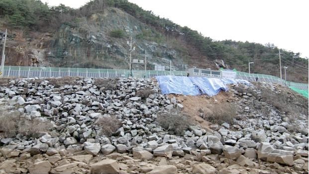 ▲ 마애불이 발견되기전 현장 모습. 40년전 도로공사 때 덮은 바위덩어리와 토사가 가득하다.