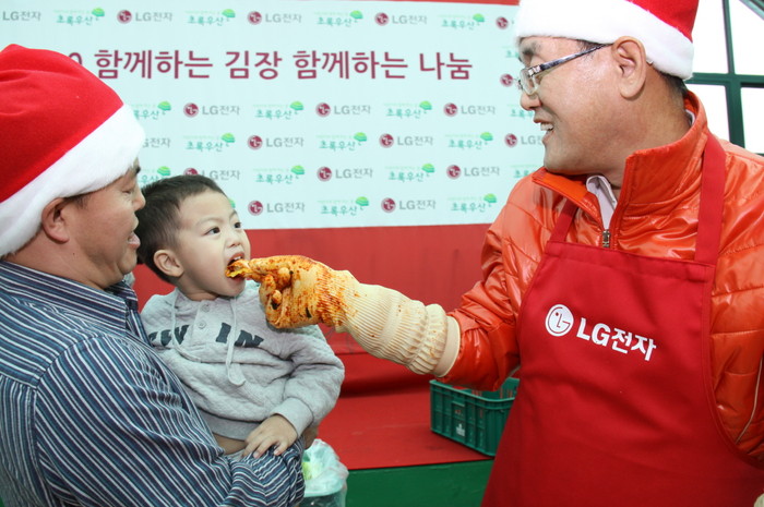 ▲ 서울 구로구 구로노인종합복지관에서 열린 ‘함께하는 김장, 함께하는 나눔’ 행사에서 LG전자 한국지역본부장 박경준 전무(오른쪽)가 다문화가정 아이에게 이날 담근 김장김치를 먹여주고 있다. ⓒ 뉴데일리