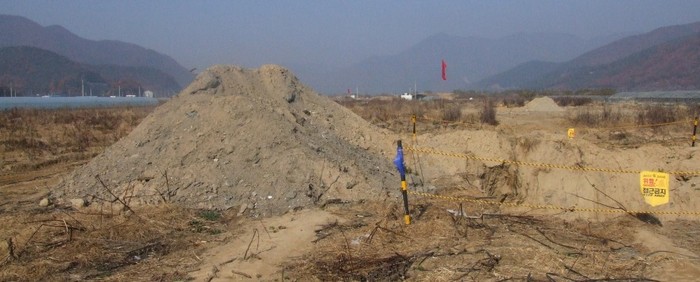 ▲ 경남 김해시 낙동강 8공구 둔치. 매립토를 퍼 올린 무더기가 보인다.  오른쪽은 낙동강이고 왼쪽은 제방 방향이다. 빨간 깃발이 있는 곳부터 강까지 긁어내 강폭을 넓힐 예정이다. 왼쪽으로 아직 수확을 마치지 않은 비닐하우스가 멀리 보인다.