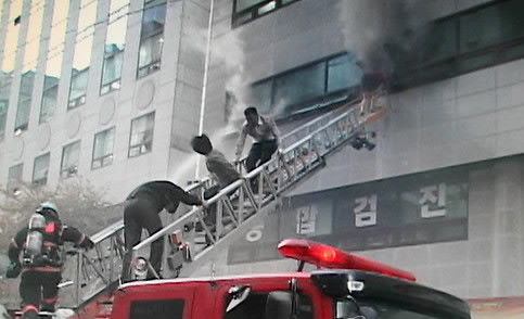 ▲ 지난 22일 강남구 삼성동 화재서 와이셔츠차림의 남기형씨가 시민들을 구하고 있다. ⓒ 연합뉴스(강남소방서 제공)