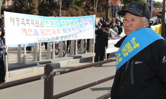 ▲ 다른 주민들이 소금을 뿌리는 동안 한 주민이 수심에 가득찬 얼굴로 국회의사당을 응시하고 있다.