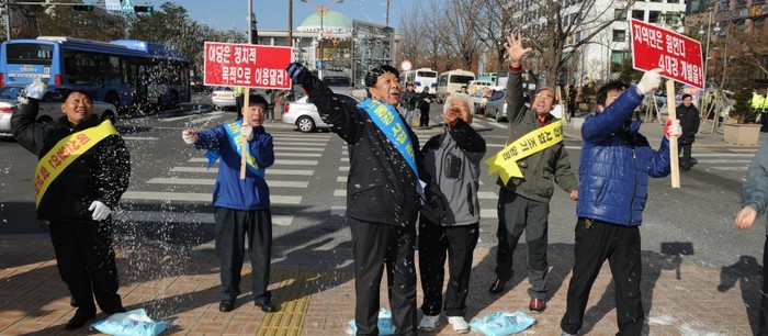 ▲ 다른 주민들이 소금을 뿌리는 동안 한 주민이 수심에 가득찬 얼굴로 국회의사당을 응시하고 있다.