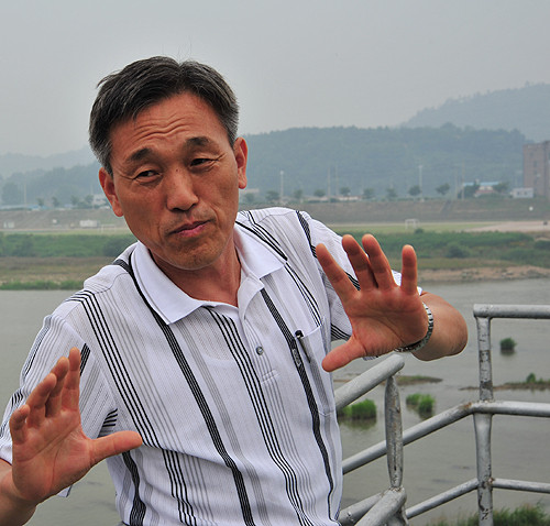 ▲ 김창원 영산강뱃길연구소장이 지난해 6월, 영산포등대 인근에서 퇴적이 심한 영산강 상황을 설명해주고 있다. 다리 난간 뒤로 준설을 하기전  영산강 바닥이 물위로 드러나있는 것이 보인다.