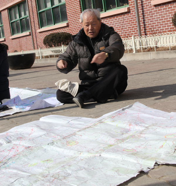 ▲ 이종창 신부가 남양주시 C초등학교에서 바닥에 대형지도를 펴놓고 땅굴의 예상 노선을 설명하고 있다.