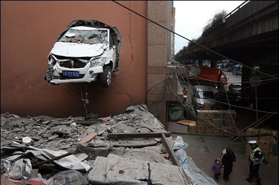 ▲ 벽을 뚫고나와 건물 벽에 간신히 걸려 있는 승용차.ⓒ온바오닷컴 캡처