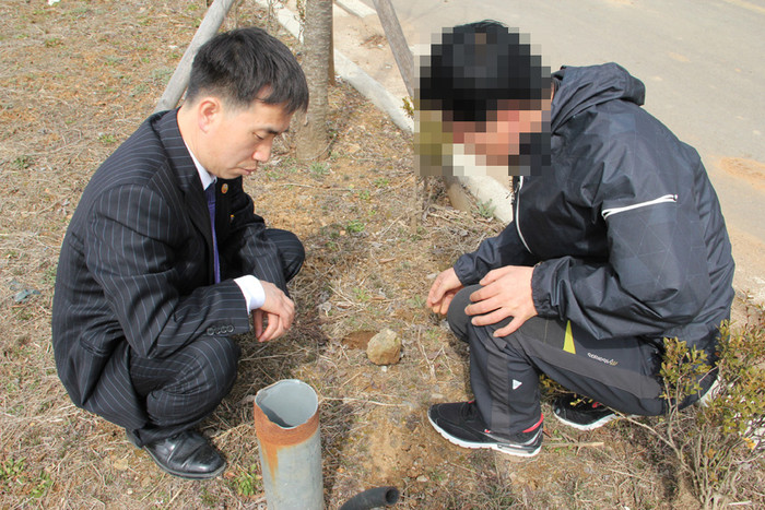 ▲ 남굴사 김진철목사 (왼쪽)가 2000년 땅굴 탐사단이 위치 확인을 위해 뚫은 지름 15cm 소형시추공을 보고 심각한 표정을 짓고 있다. 김신기 기자.