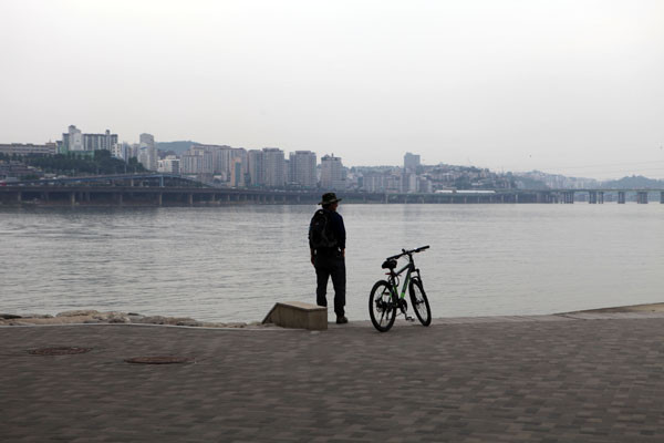 ▲ 자전거를 세워두고 한강을 바라보며 여유로움을 즐기고 있다. ⓒ노용헌기자