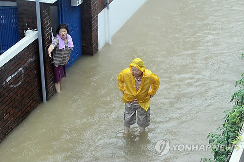 ▲ 27일 오전 서울지역에 밤새 내린 호우로 서대문구 북가좌2동의 한 주택가의 하수구가 역류해 인근 주택가가 물바다가 됐다. 주민들이 물에 잠긴 골목을 힘겹게 걷고 있다.ⓒ연합뉴스