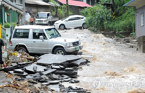 ▲ 사진 = 지난 27일 오전 강원 춘천시 신북읍 천전리 소양강댐 인근 야산에서 산사태가 발생, 많은 인명피해가 발생한 가운데 소양강댐 입구 앞 마을 도로에 급류가 흘러내리고 있다.